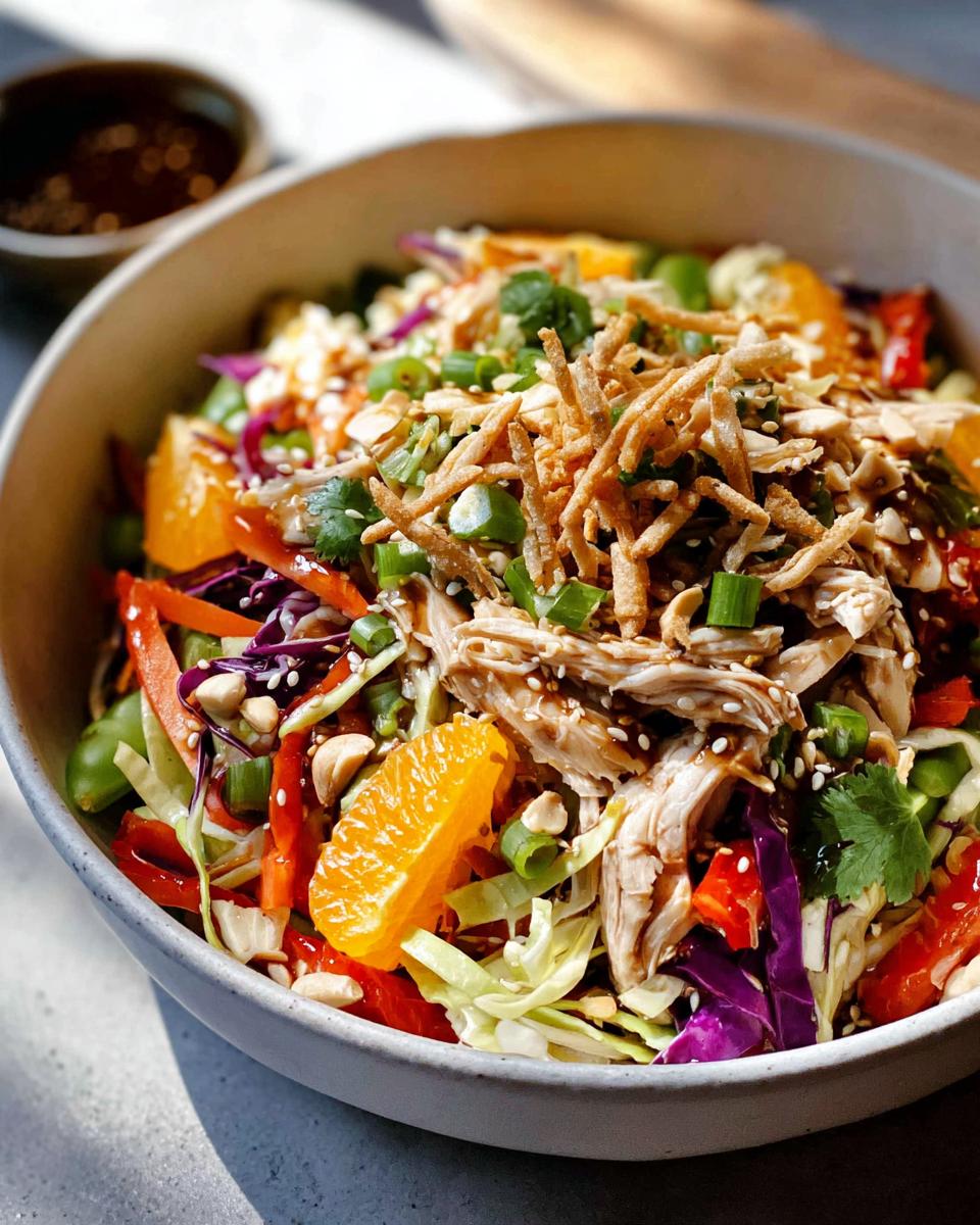 Irresistible Chinese Chicken Salad with 25-Minute Magic 4 A colorful bowl of Chinese Chicken Salad featuring shredded chicken, mandarin oranges, cabbage, peppers, and crispy noodles.