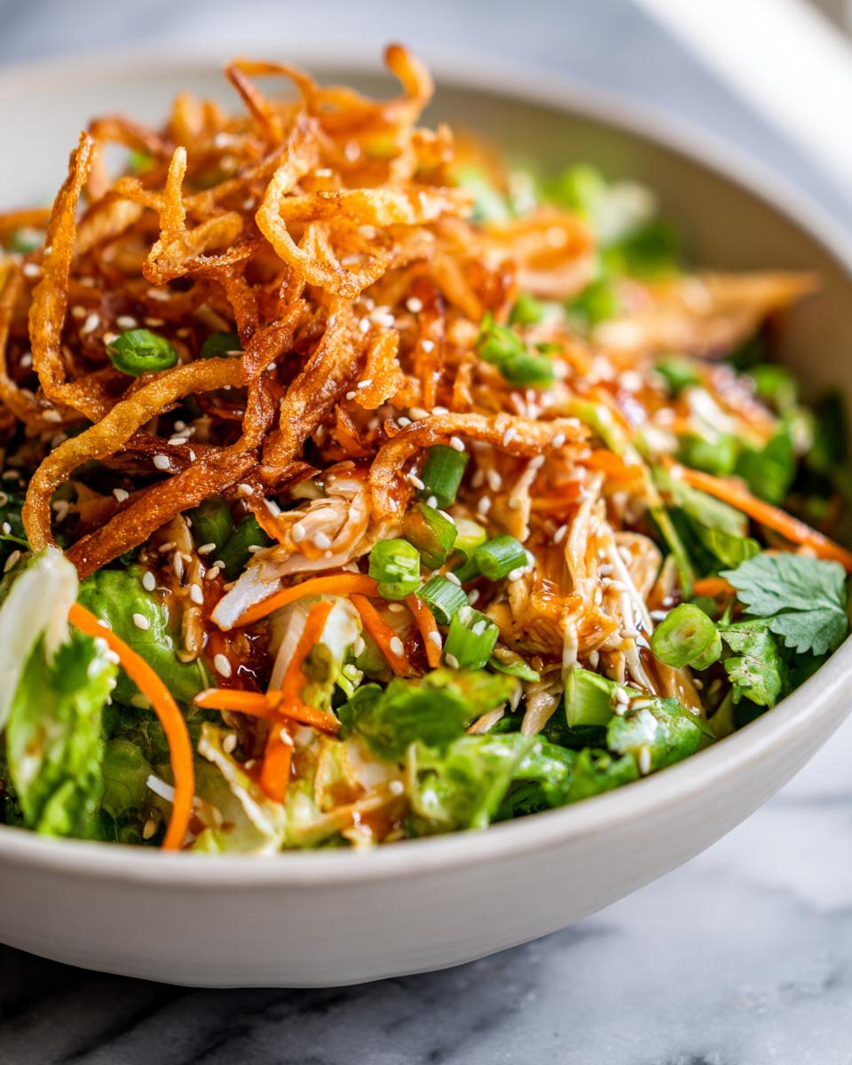 25-Minute Chinese Chicken Salad Crispy Sesame Ginger Recipe 5 Close-up of a Chinese Chicken Salad with crispy fried onions, sesame seeds, and scallions.