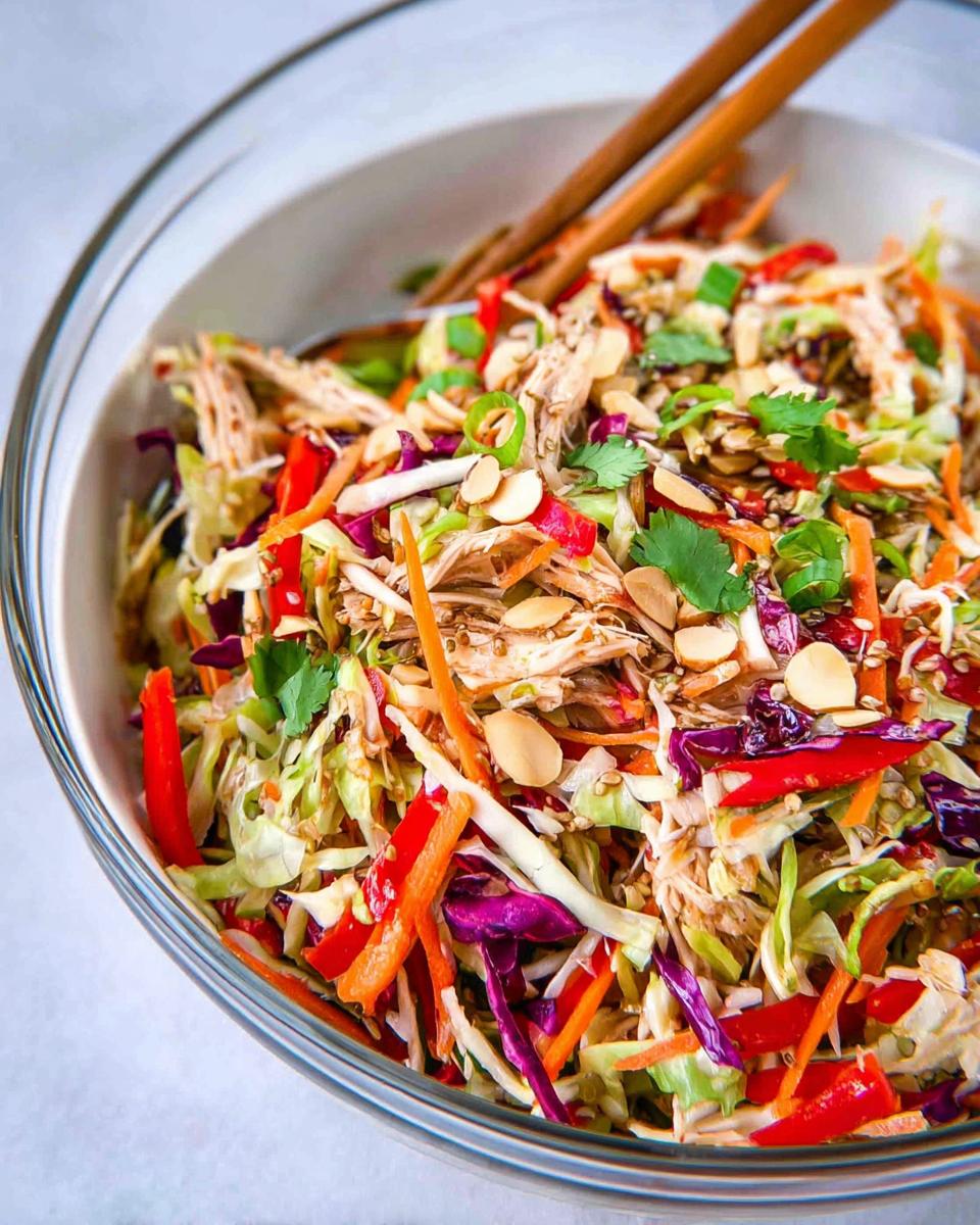Your 30-Minute Chinese Chicken Salad with Sesame Dressing 5 A vibrant Chinese Chicken Salad with Sesame Dressing in a glass bowl, featuring shredded chicken, colorful vegetables, and crunchy almonds.
