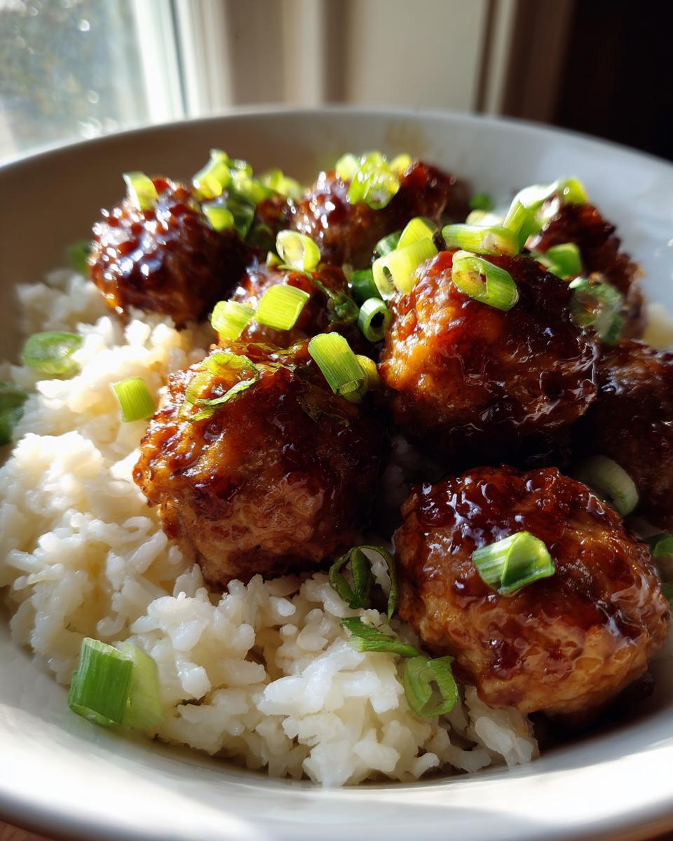 Amazing Honey Garlic Chicken Meatballs in 40 Mins 4 Close-up of glistening honey garlic chicken meatballs served over fluffy white rice and garnished with chopped green onions.